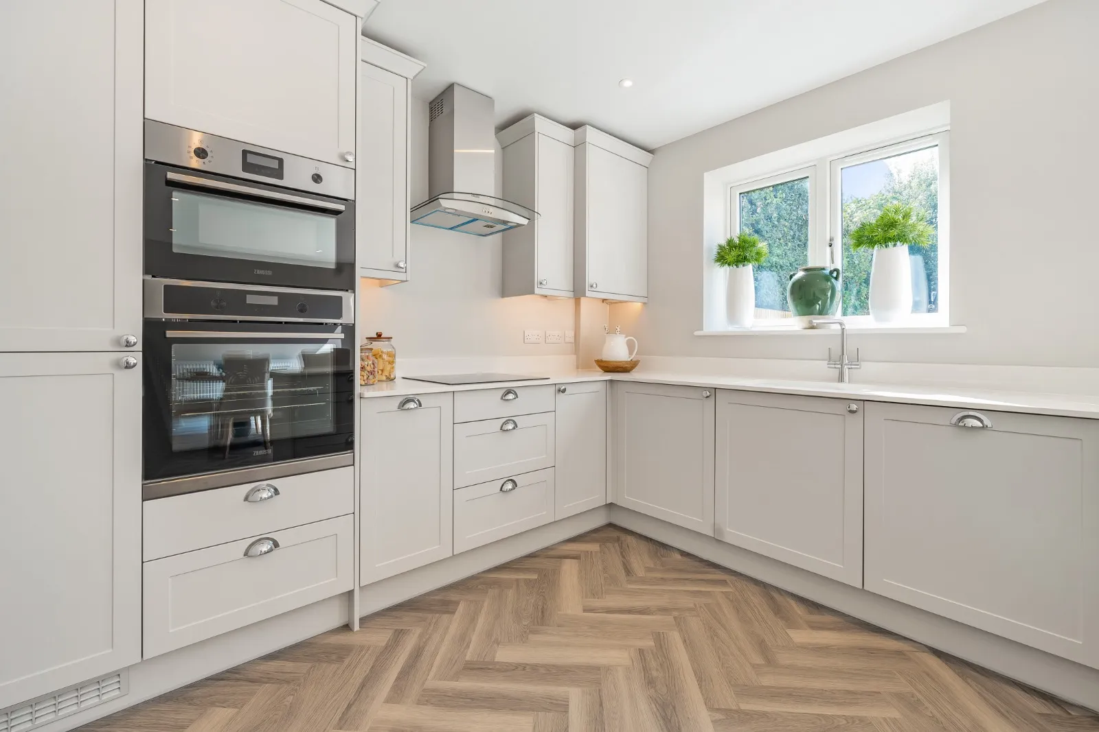a kitchen with white cabinets and wood flooring