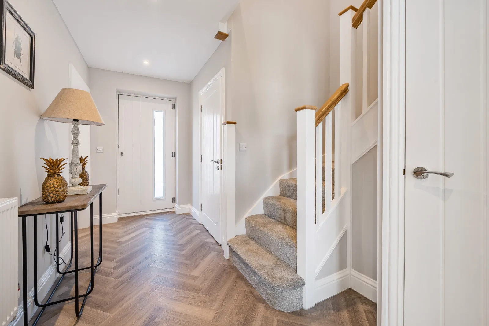 a hallway with a staircase and a table with a lamp on it