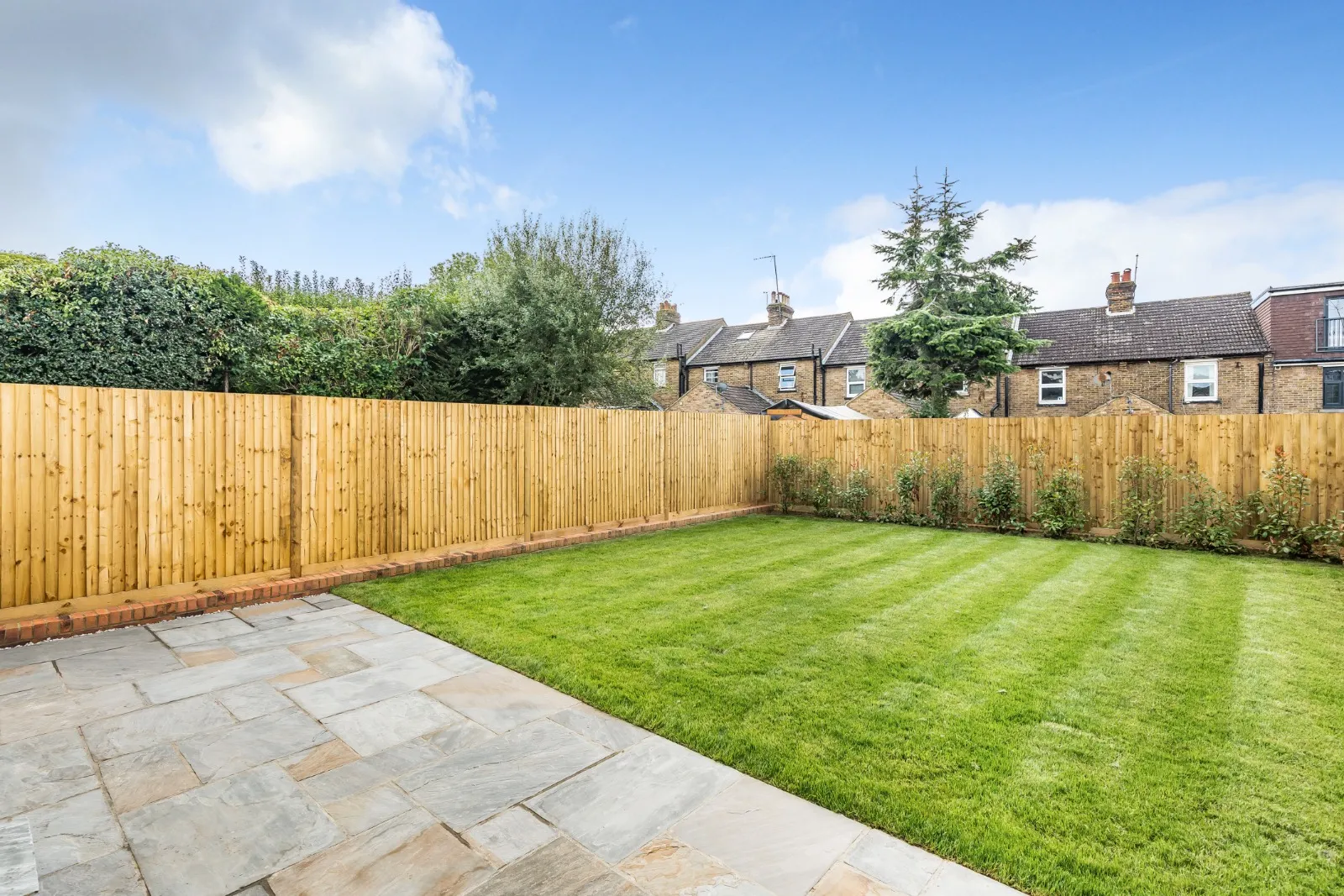 a backyard with a wooden fence and green grass